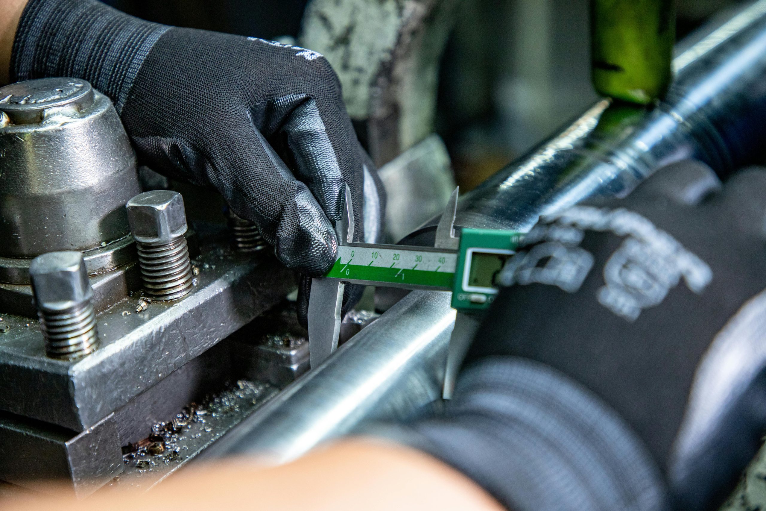 Close-up of a mechanic using a caliper on machinery, emphasizing precision in engineering.